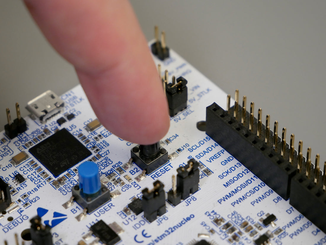 A finger pressing a button on a development circuit board