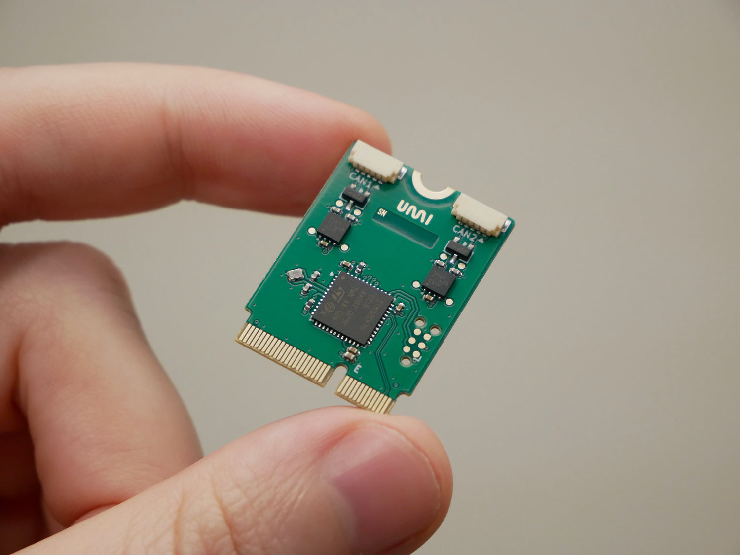 M.2 CAN FD Adaper card held between two fingers.